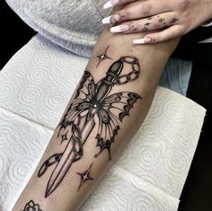 a woman's arm with a tattoo on it and a knife in the middle