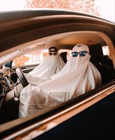 two people wearing white cloths in the back of a car