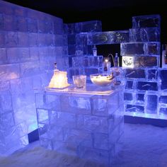 an ice hotel with lots of cubes and bottles on the counter, all lit up