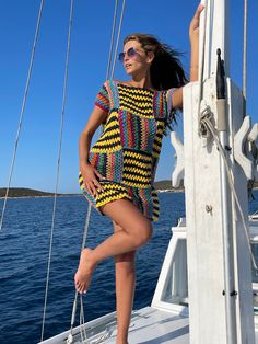 a woman standing on the deck of a sailboat wearing sunglasses and a colorful dress