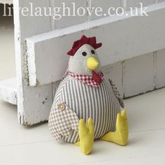 a stuffed chicken sitting on the ground next to a white brick wall and window sill