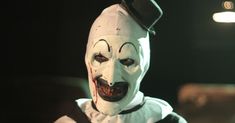 a man dressed as a clown wearing a top hat and white face paint on his head