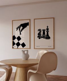 two framed pictures on the wall above a table with chairs and a vase in front of it