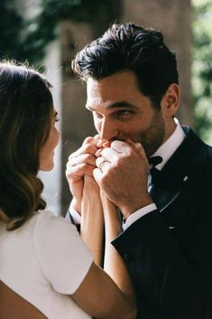 a man and woman standing next to each other with their hands on their mouths while looking at each other