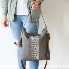 a woman holding a gray purse with brown handles