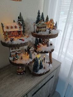 three tiered trays with christmas decorations on top of a wooden table in front of a window