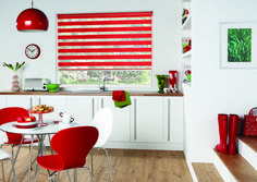 a white kitchen with red chairs and a round table in front of a window that has blinds on it