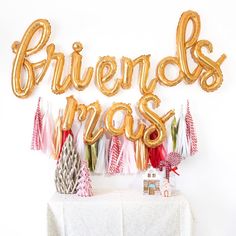 a white table topped with gold balloons and streamers that say friends pass on top of it