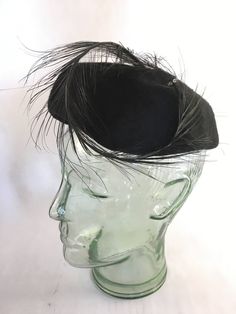 "This is a simple, but elegant black hat with a wonderfully swooped black feather perched on it! The feather is attached in the back with a decorative bow, and gracefully curls to the left side of the hat, with a rhinestone bead holding it in place. This hat is in excellent vintage condition, is clean & ready to wear.  Measures 6.5\" wide." Elegant Black Feather Trim Costume Hat, Elegant Black Costume Hat With Feather Trim, Black Feather Trim Mini Hats For Kentucky Derby, Black Mini Hats With Feather Trim For Kentucky Derby, Fitted Black Fascinator With Feather Trim, Black Mini Hat With Feathers And Curved Brim, Black Feathered Evening Hat, Elegant Black Mini Hat With Feather Trim, Black Feather Trim Hat For Kentucky Derby