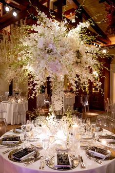 an elegant centerpiece with white flowers and greenery is displayed on a round table