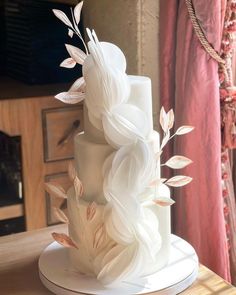 a white wedding cake with leaves on top