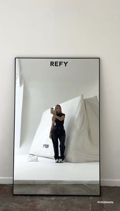 a woman taking a selfie in front of a white backdrop with the words refy on it