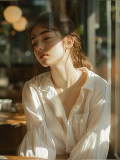 a woman sitting at a table with her hands on her hips looking out the window