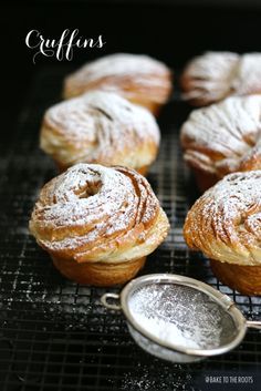 several pastries sitting on top of a cooling rack next to a scoop of powdered sugar