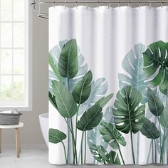 a white shower curtain with green leaves on it in front of a bathtub and window