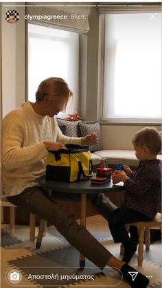 a man sitting at a table with a child in front of him and holding a bag