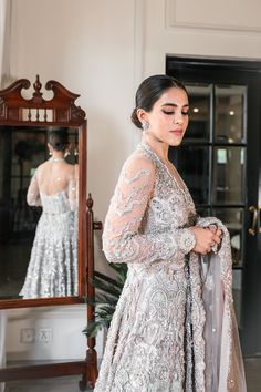 Pakistani Bridal Walima Dress in Gown Lehenga Style has an alluring silver-grey shade and it is gracefully emblazoned with intricate designs and fine details of embellishments. Perfect stitching and premium quality fabric make this Pakistani Bridal Dress an epitome of beauty. Pakistani Bridal Gown: Pakistani Bridal Gown is adorned with hand-crafted details of beaming silverwork, zardosi, pearls, and sequins. This Pakistani Bridal Dress is fully emblazoned with shimmering ornaments and motifs, ma Bridal Walima Dress, Pakistani Bridal Outfits, Walima Gown, Gown Lehenga, Pakistani Gown, Pakistani Bridal Lehenga, Wedding Dresses Pakistani, Bridal Mehndi Dresses, Pakistani Bridal Dress