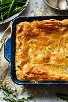 a casserole in a blue dish with green beans and asparagus