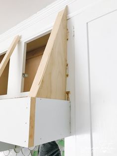 an unfinished kitchen cabinet is being built into the wall by someone holding it up with their hands