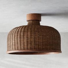 a wooden light hanging from the ceiling with wicker shades on it's sides