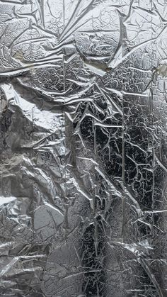 an abstract photograph of snow and ice on a window pane with trees in the background