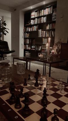 a chess board with pieces on it in front of a bookshelf