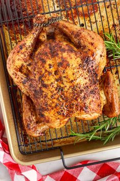 a whole chicken on a grill with rosemary sprigs