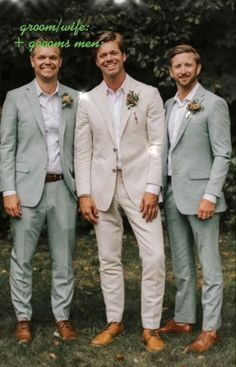 three men in suits and ties standing next to each other on the grass with trees in the background