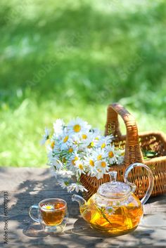 tea and daisies in a wicker basket on a picnic table