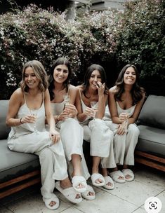 four beautiful women sitting on top of a couch next to each other holding wine glasses