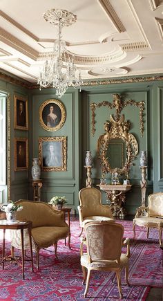 a living room filled with lots of furniture and paintings on the wall next to a chandelier