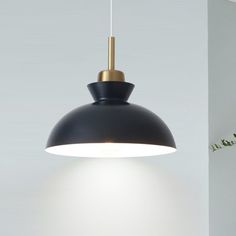 a black and gold pendant light hanging over a white table with flowers in vases