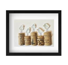 three birds sitting on top of corks with the word love spelled in black frame