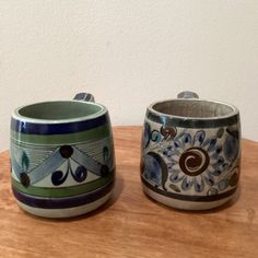 two ceramic cups sitting on top of a wooden table