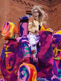 a woman sitting on top of an elephant made out of crocheted yarns