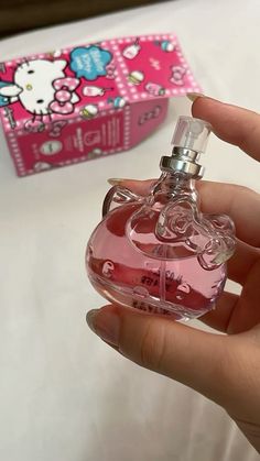 a person holding a pink hello kitty perfume bottle