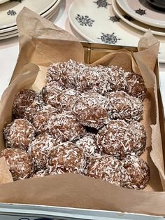 a box filled with chocolate covered donuts on top of a table next to plates