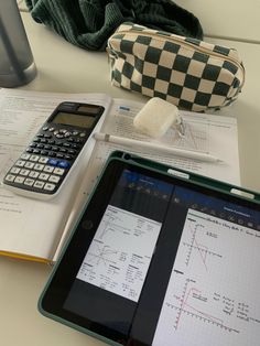 a tablet computer sitting on top of a desk next to a calculator and notebook