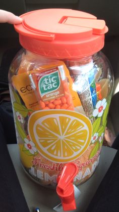 a jar filled with assorted snacks sitting on top of a car seat next to a person's hand