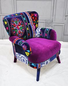 a purple chair sitting on top of a white floor next to a gray wall and wooden doors