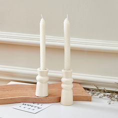 two white candles sitting on top of a table