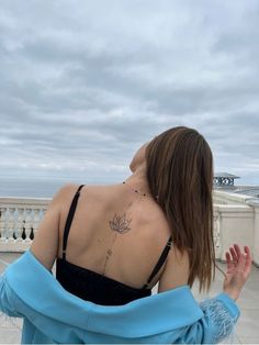 the back of a woman's body with a lotus tattoo on her left shoulder