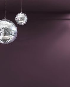 three disco balls hanging from the ceiling in front of a purple wall with lights on it