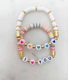 two bracelets that say i love you and have hearts on them with gold beads