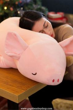 a woman laying on top of a pink pig pillow