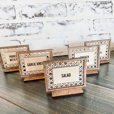 four wooden signs with arabic writing on them sitting on a table next to a brick wall