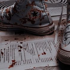 a pair of shoes sitting on top of a newspaper with blood all over the floor