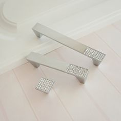 two silver handles with diamonds on them in a bathroom