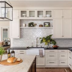 a kitchen with white cabinets and marble counter tops, along with a wooden cutting board