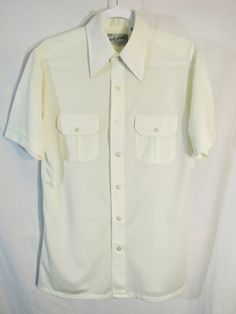 "Here's the second one of these. They came together. One is peachy gold! It's a 1970's Port of Call by Van Heusen Men's Short Sleeve Button Shirt. Tag Size M, Light Yellow cream.  Shiny buttons. HUGE pointy collar. Like the other one, it looks like it was worn a few times and that was it. They are in just amazing condition! Measurements: Label size: Medium Shoulder-to-shoulder: 18\" Chest across: 21.5\" Waist across: 19\" Sleeve from shoulder seam: 9.5\" Back length: 29\" Have a look at our othe Cream Short Sleeve Shirt With Button Closure, Classic Cream Collared Shirt, Retro Button-up Formal Shirt, Retro Button-up Shirt For Formal Occasions, Formal Collared Shirt With Snap Buttons, Cream Short Sleeve Shirt With Buttons, Cream Collared Shirt With Button Closure, Retro Fitted Collared Camp Shirt, Fitted Collared Retro Camp Shirt